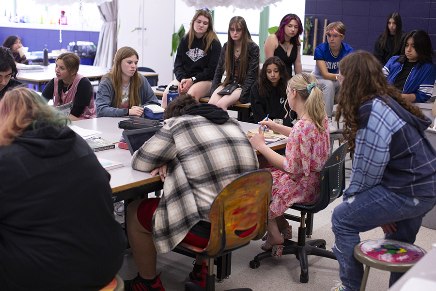 Students sit around Hollyn in an art room as she paints.