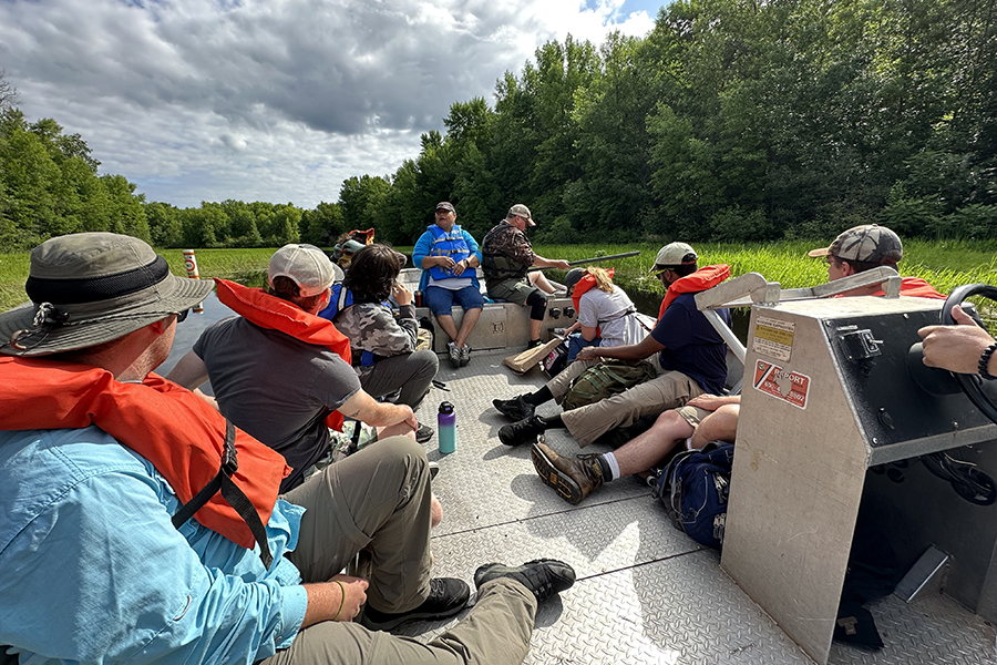 People ride on a boat tour through a wooded river near Lake Superior.