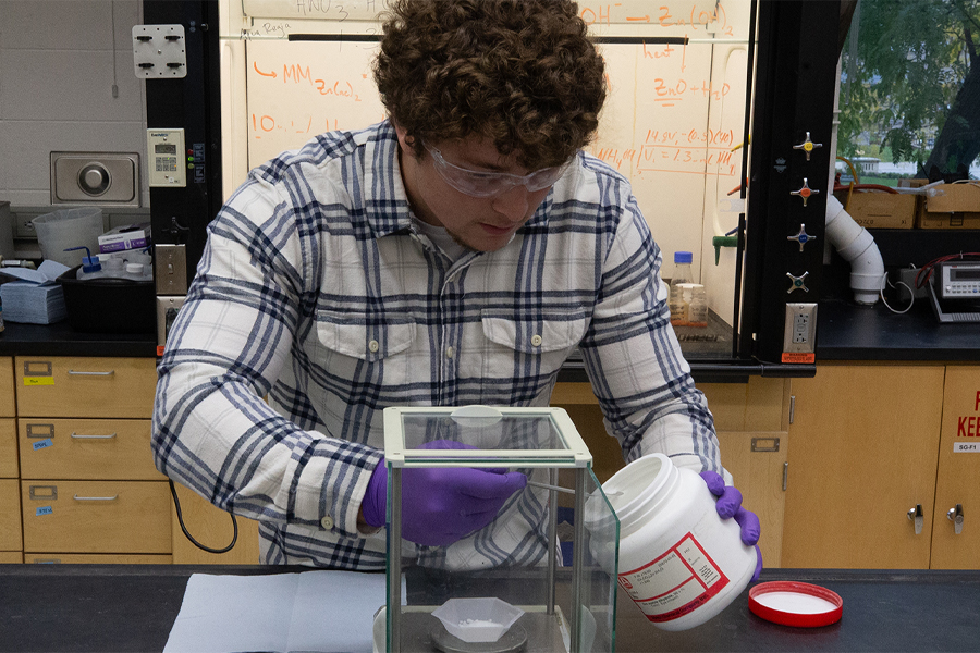 A student works in a lab while wearing safety glasses.