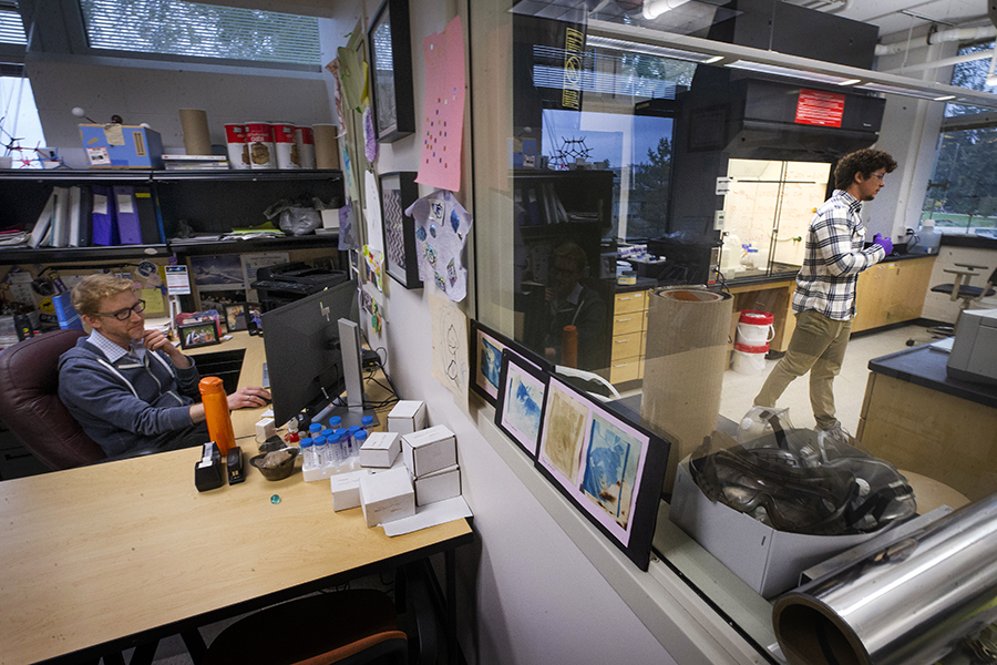 Barmore is reflected in a mirror by Associate Profession Girard's desk.