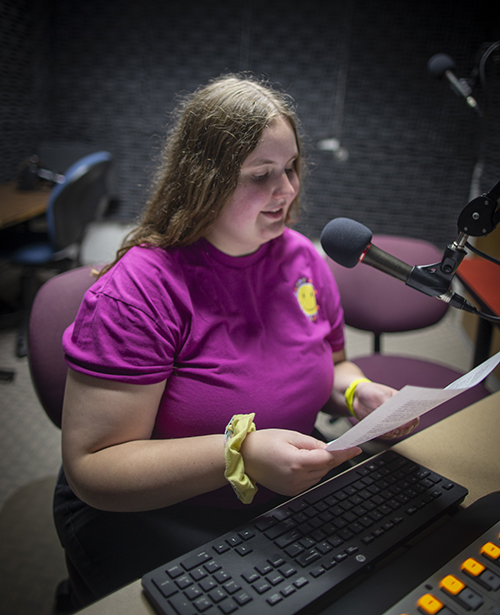 Carchesi sits in front of a microphone with paper in her hands.