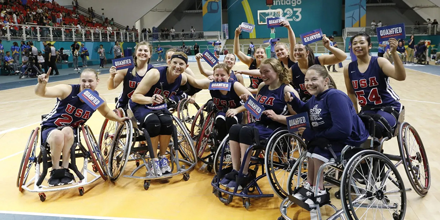 Women's Team USA lines up and smiles for the camera holding posters that say qualified.