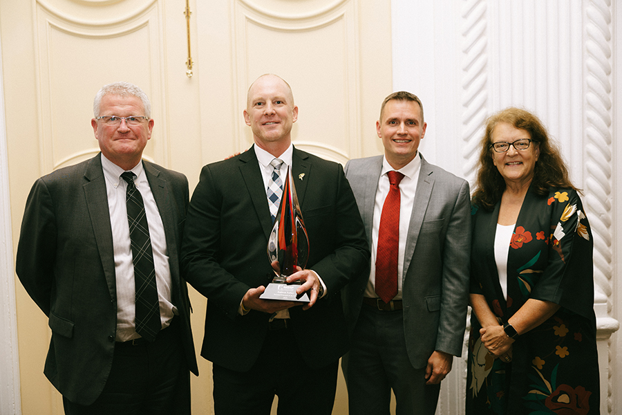 Andy Farley stands in a group holding an award.