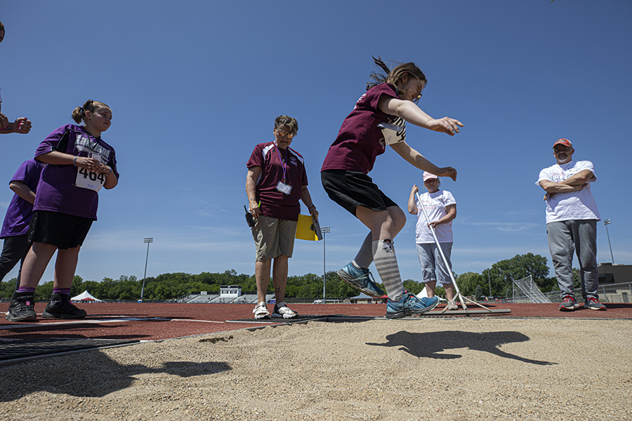 An athlete jumps into the sand while competing in the long jump.