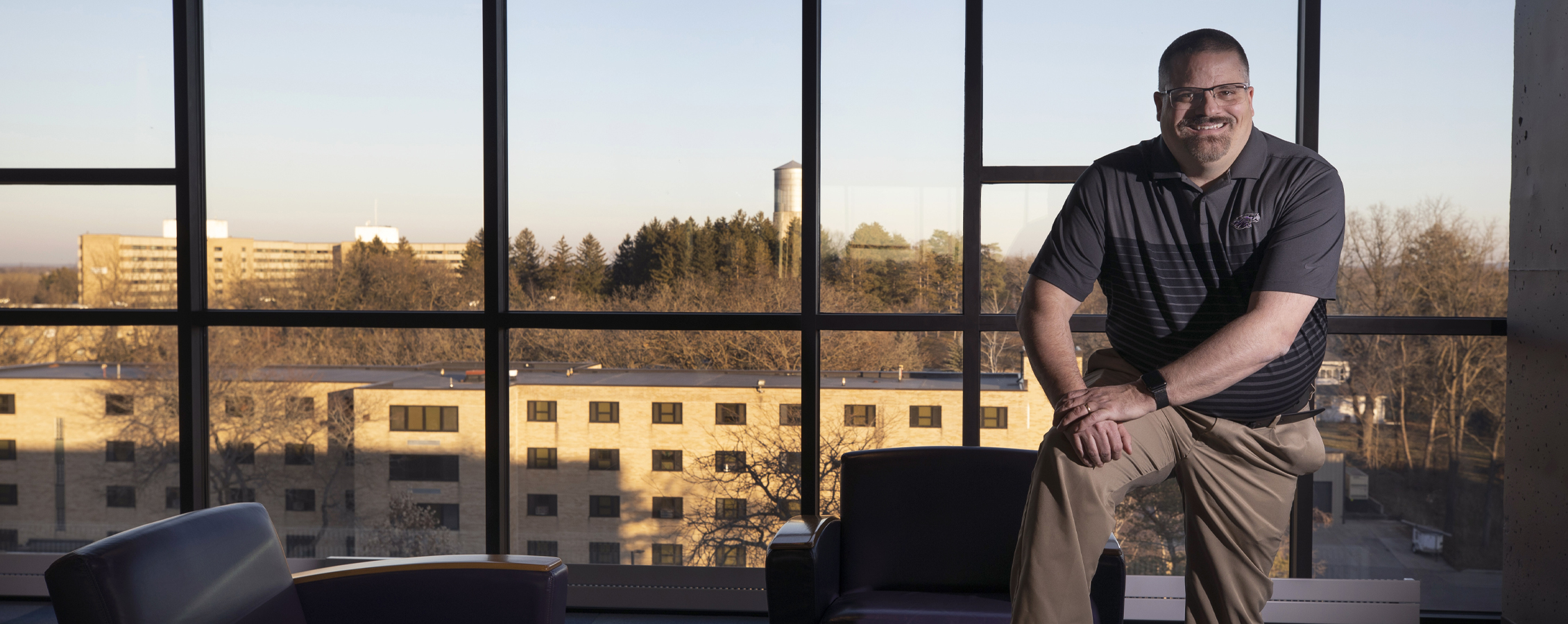 Terry Tumbarello stands in Ma'iingan Hall by a wall of windows.