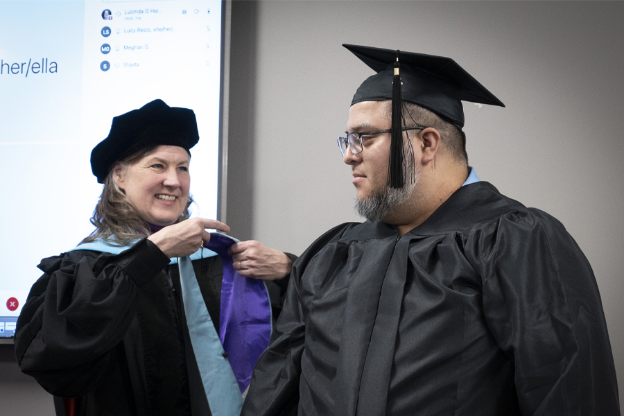 A graduate recieves an academic hood during a hooding ceremony.