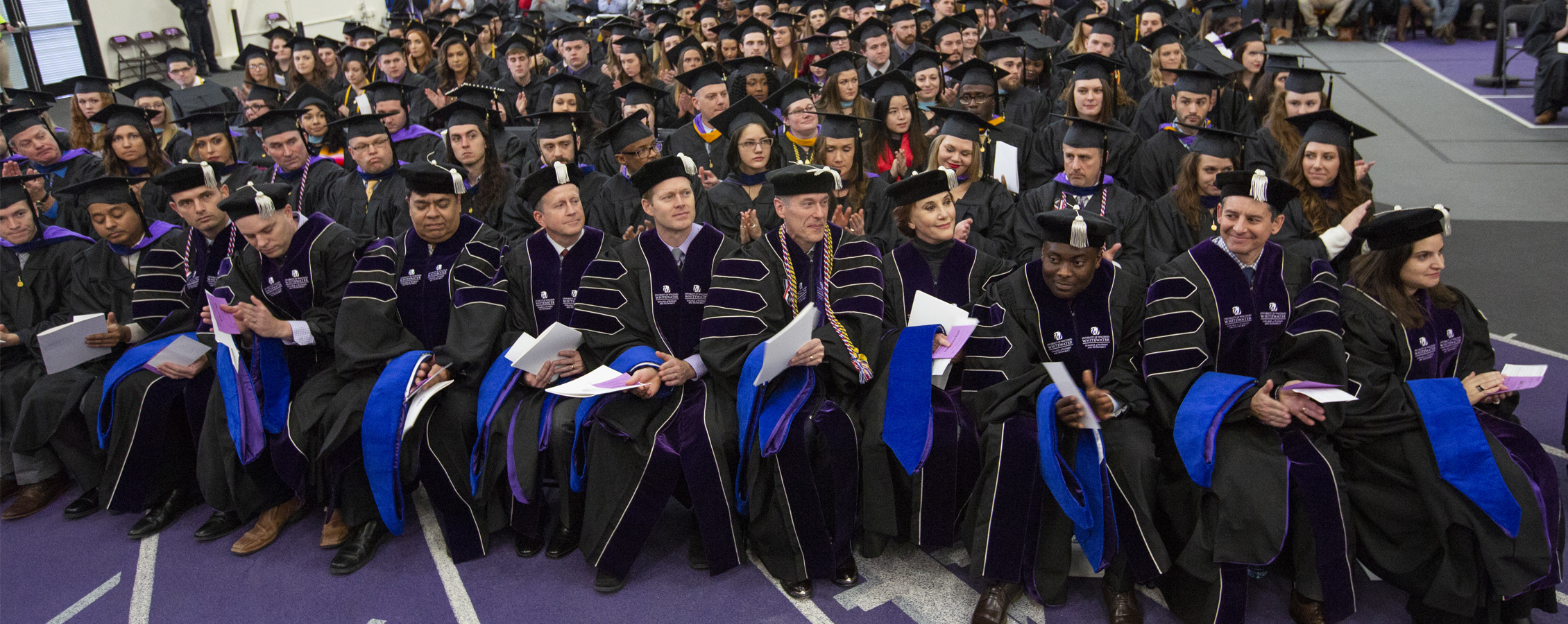 Members of the first cohort of Doctor of Business Administration graduates at UW-Whitewater sit in the front row at commencement.