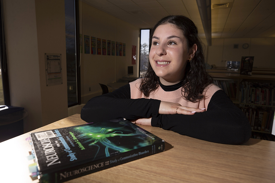 A student sits at a table with a book titled Neuroscience in front of her.