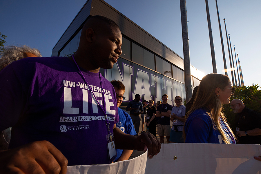 Kevin Walther, wearing a LIFE t-shirt, helps to hold a white banner.