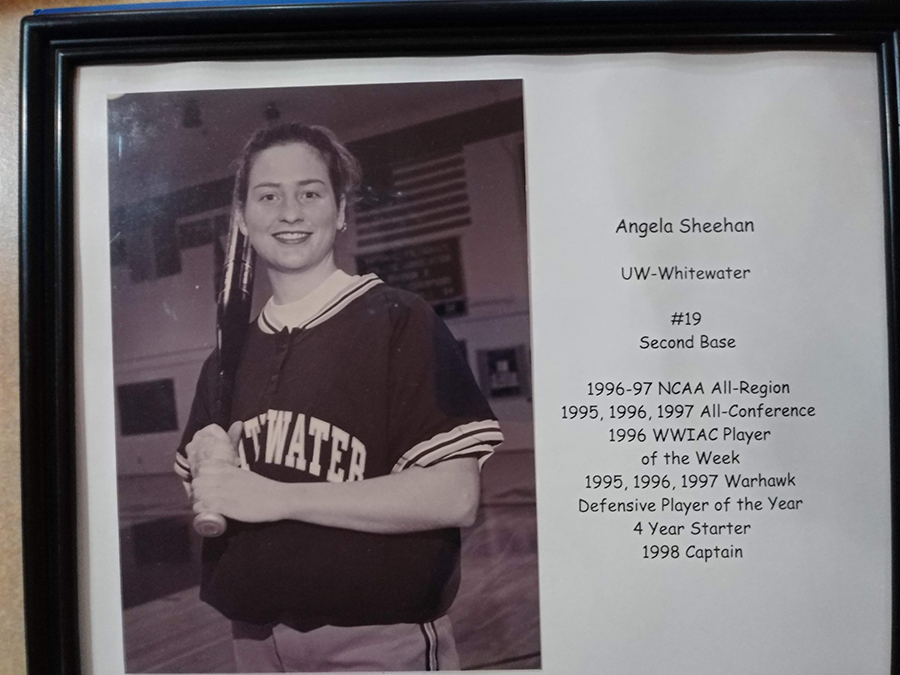 A framed black and white photo of Rachidi in college dressed in a softball uniform.