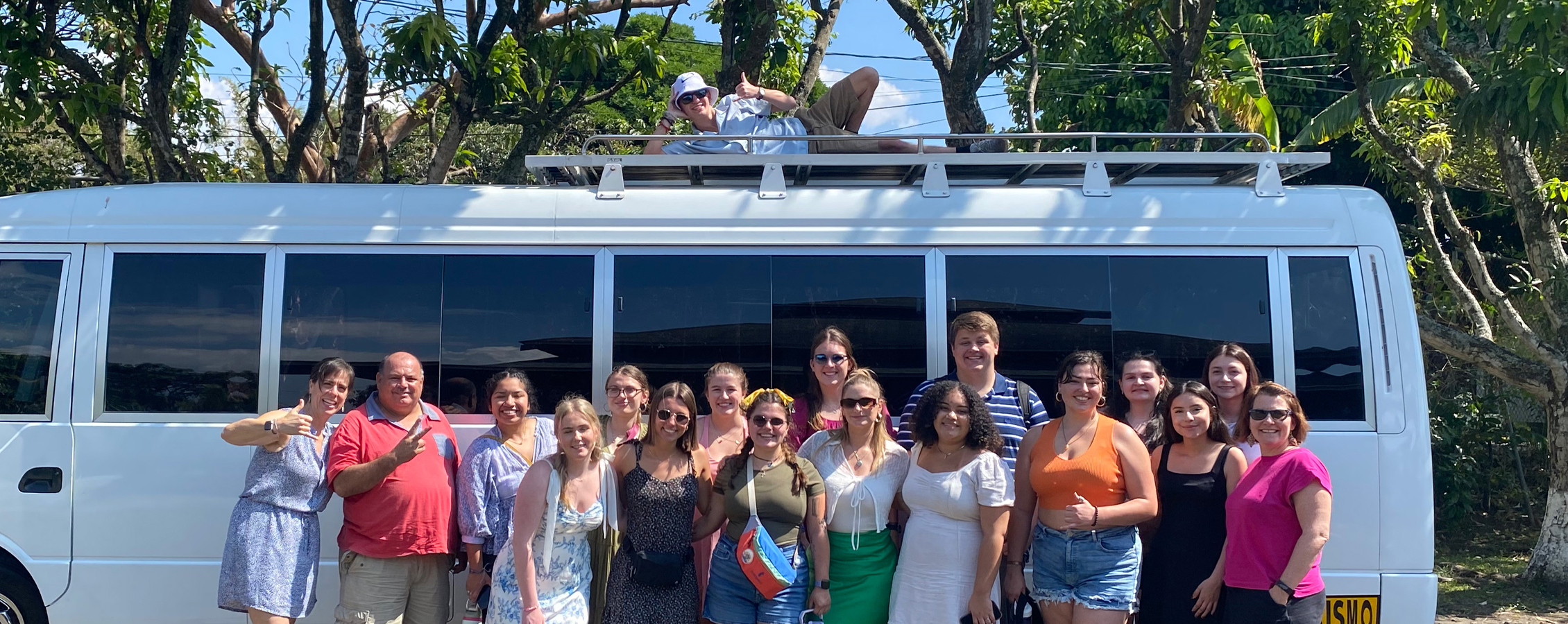 Students and faculty stand in front of a white van in Costa Rica.