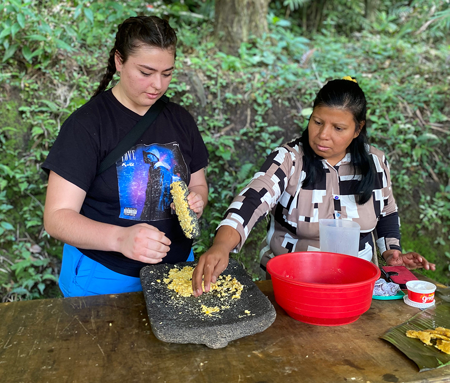 Two people with ingredients laid out on a table outdoors.