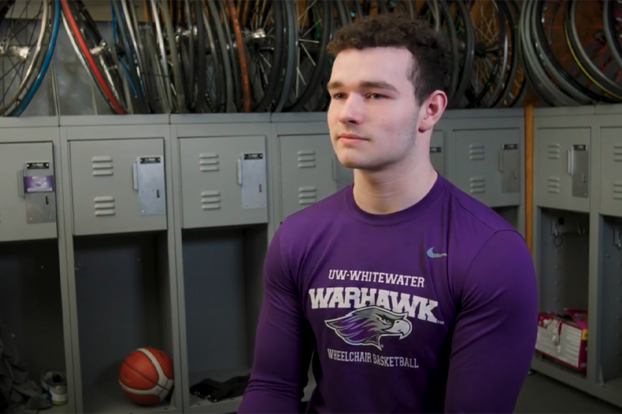 AJ Fitzpatrick sits in the front of the camera wearing a purple shirt.
