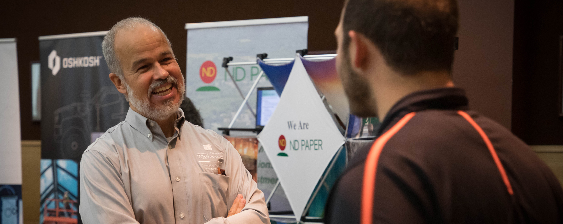 A faculty member smiles and chats with a student.