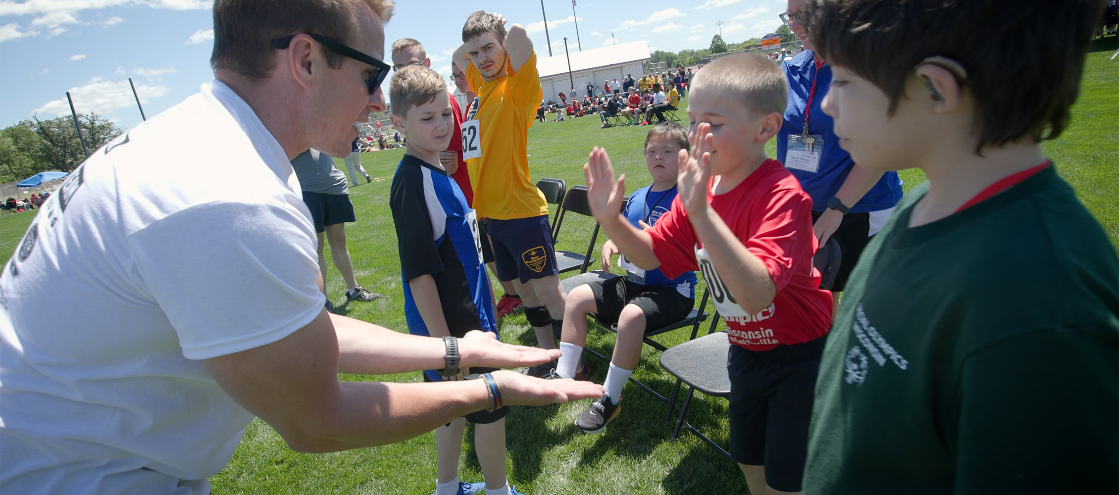 A person in a white shirt high-fives children standing in a line.