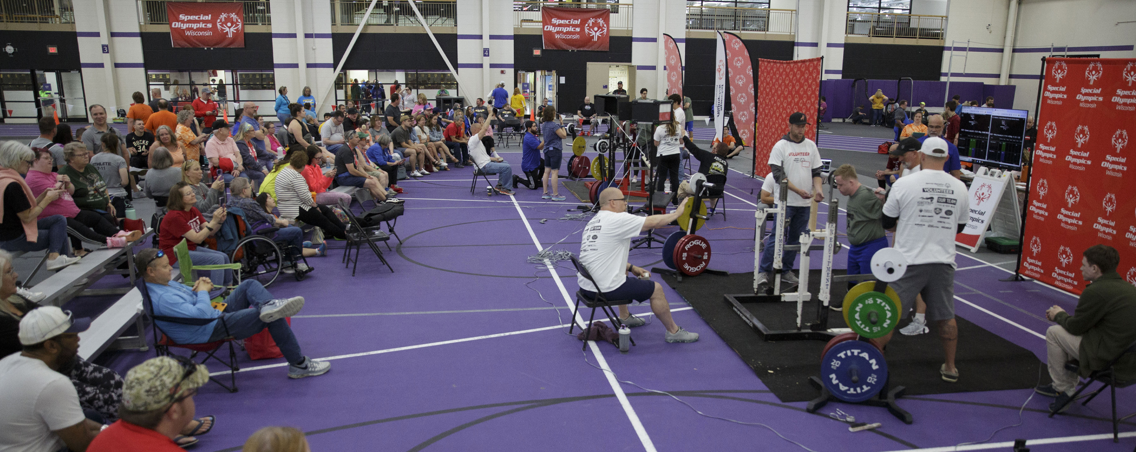 Crowds of people watch an athlete weighlift.