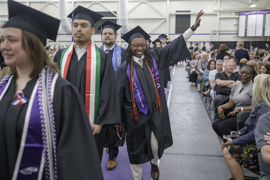 A student wearing academic regalia waves during the graduation ceremony.