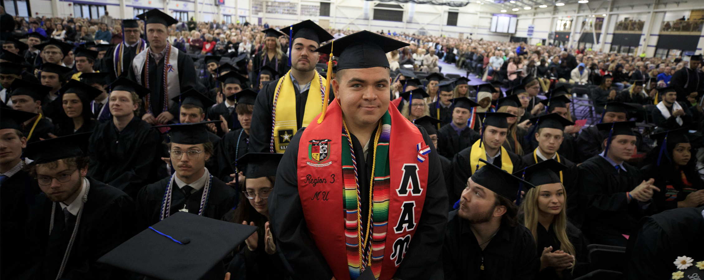 Group of college students wearing caps and gowns at graduation.
