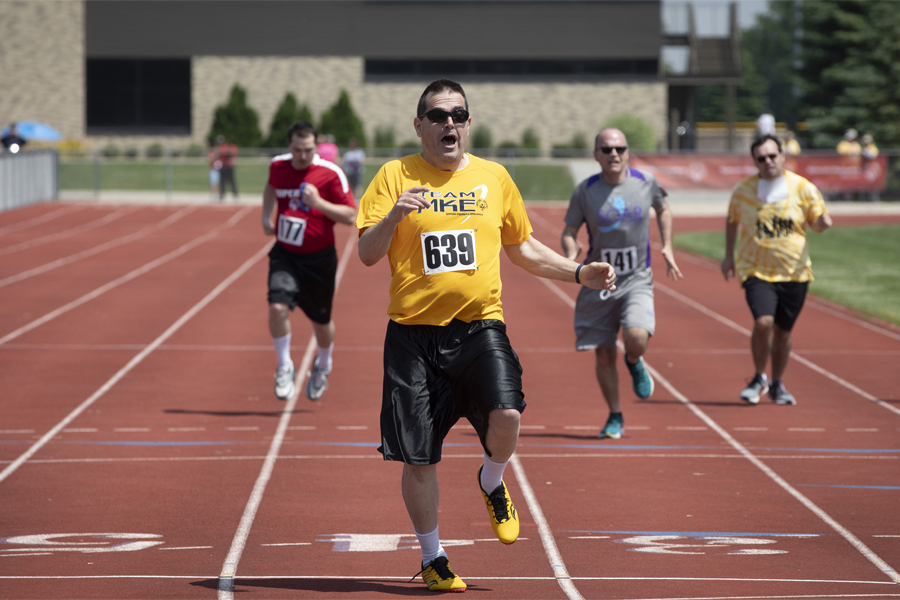 Athletes running on track during Special Olympics race.