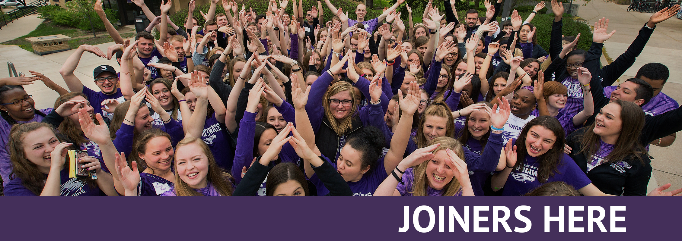 Joiners Here: A group of about 30 peer mentors with their hands raised.