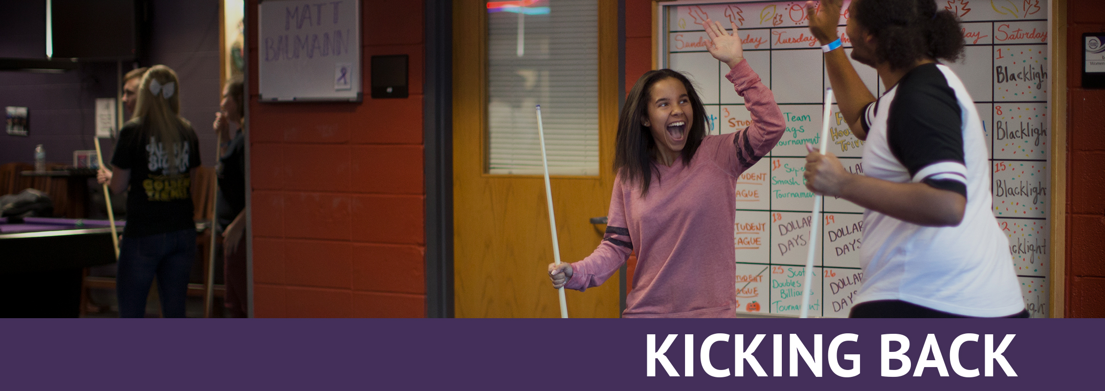 Kicking Back: Two students high fiving as they play billiards