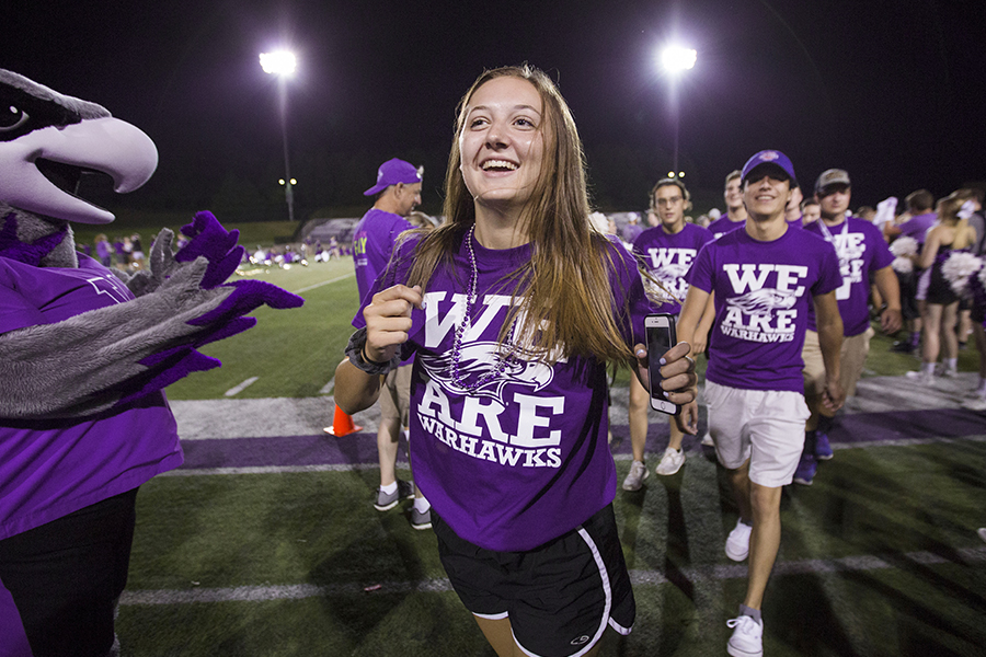 Students run past Willie on the football field during RU Purple.
