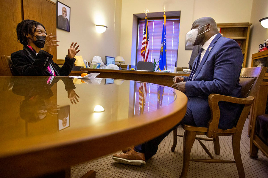 Shalea Carter sits at a desk and speaks to a lawmaker.