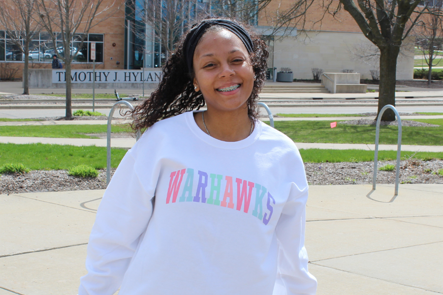 A female student stands outside wearing a Warhawks sweatshirt.