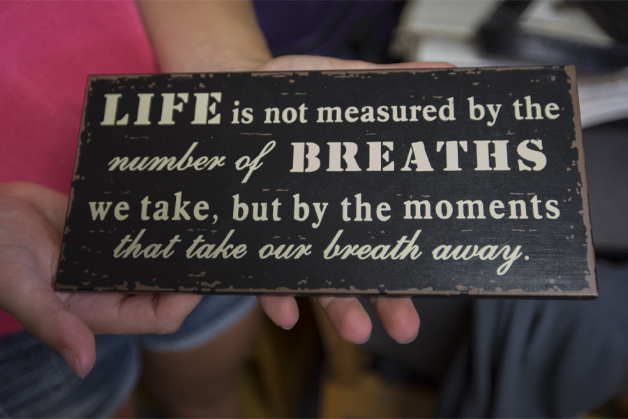 A person holds a sign that says Life is not measured by the breaths we take, but the moments that take our breath away.