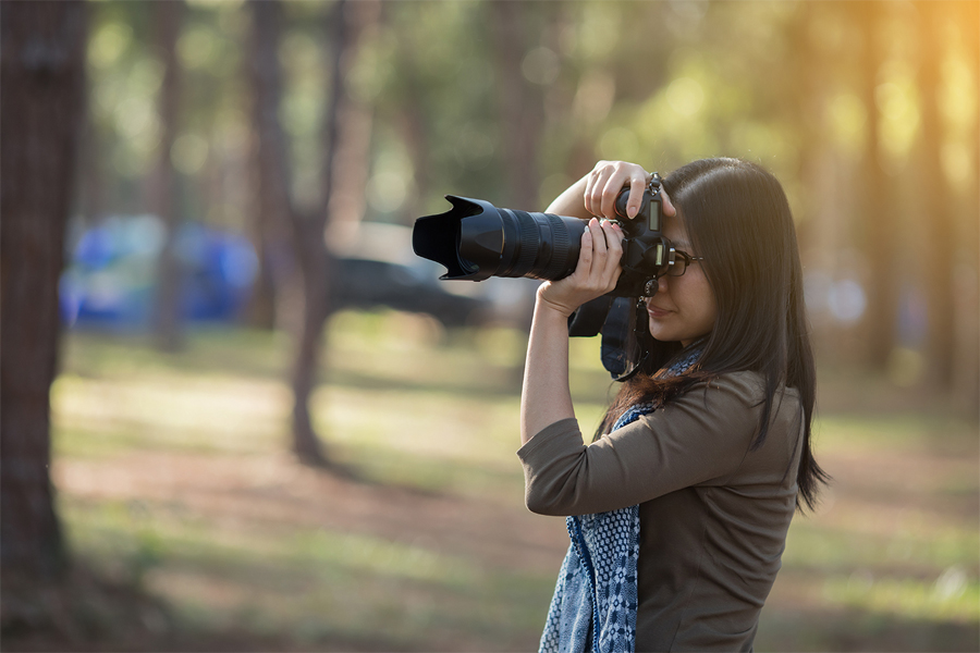 Photo of a person holding a camera with a large telephoto lens.