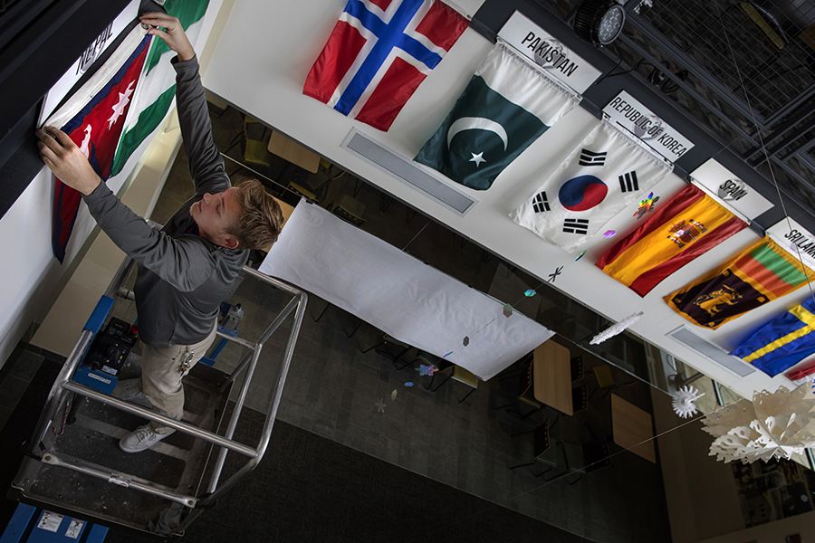 A student worker hangs international flags in the University Center.