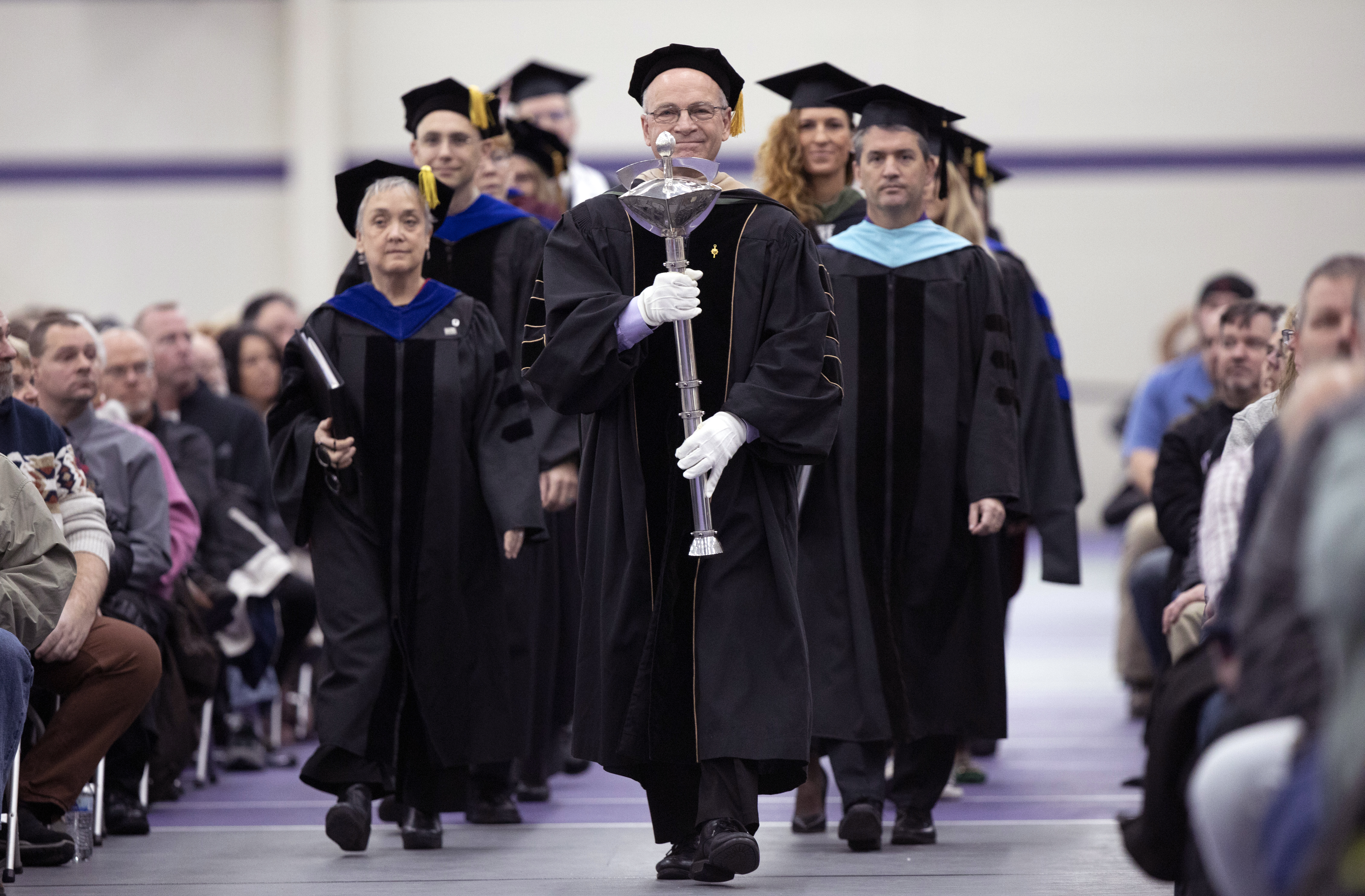 Faculty members walk into the fieldhouse at graduation.