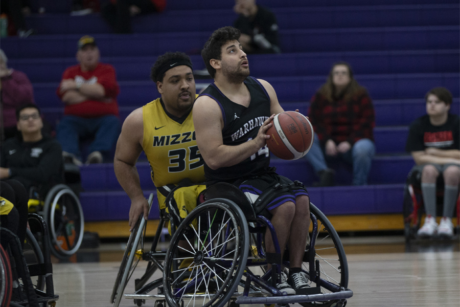 A wheelchair basketball player shoots the ball.