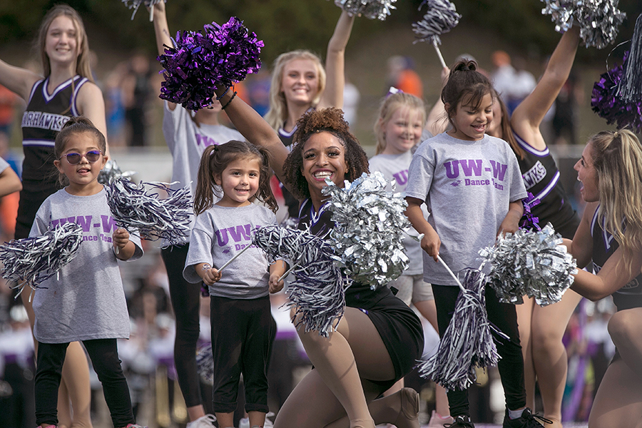 Warhawk Dance members smile and pose with children holding poms. 