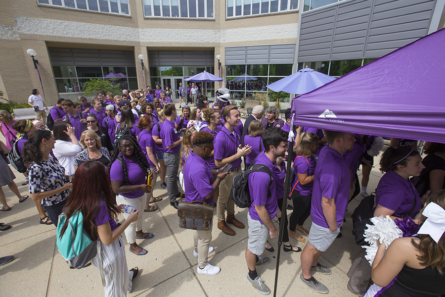 People in purple shirts stand outside the University Center.