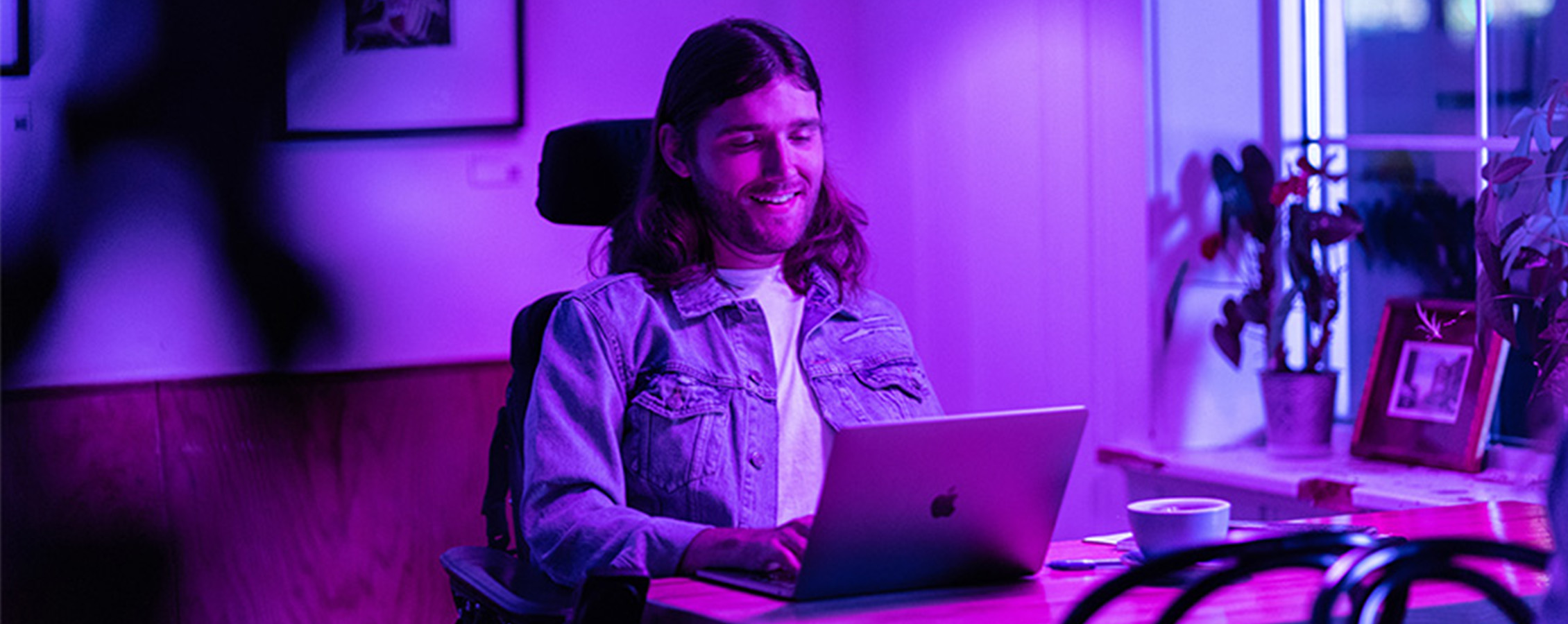 Young man in wheelchair working on laptop for online college  class