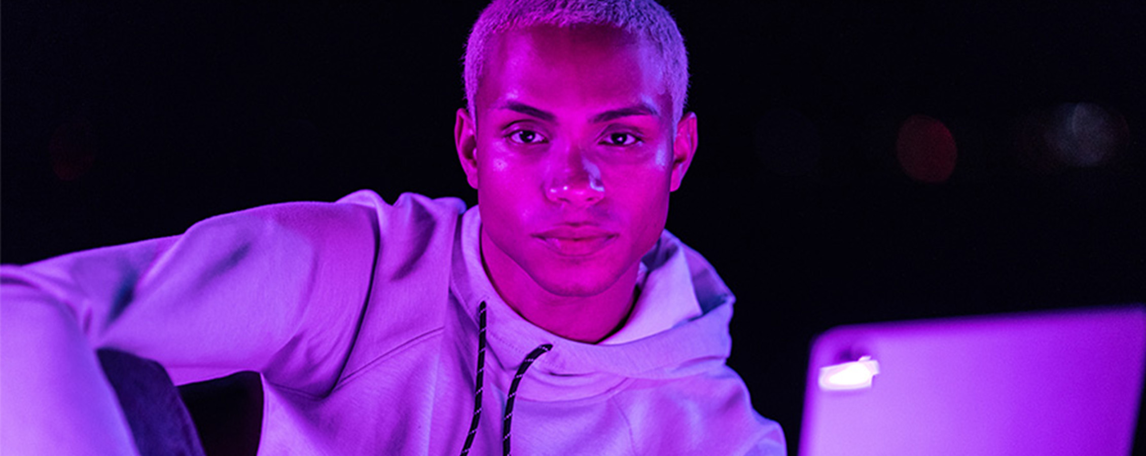 Young man reading tablet in purple light for online  college class