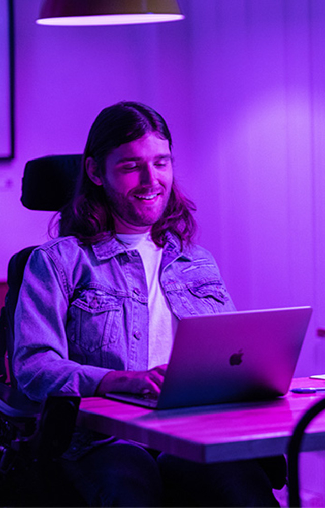Young man in wheelchair working on laptop for online college  class