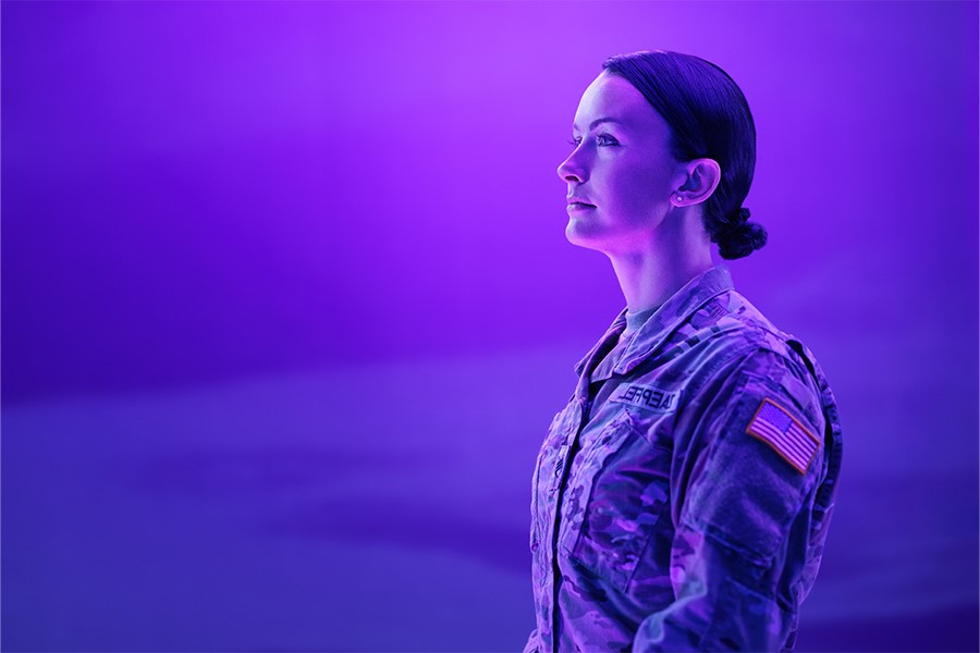 A person in a purple light looks off into the distance.