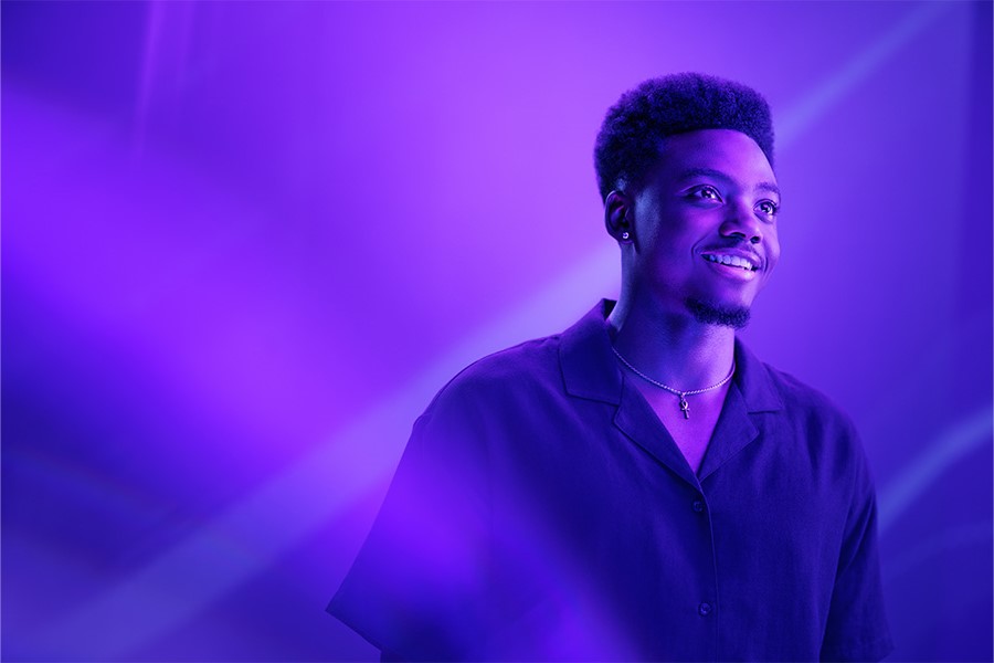 A person in a purple light looks off into the distance.