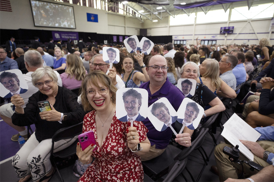 A family holds signs of their son's face during commencement.