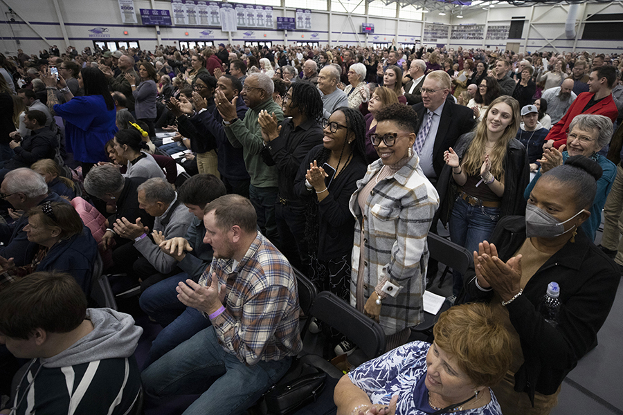 People stand by their seats in the field house during a commencement ceremony.