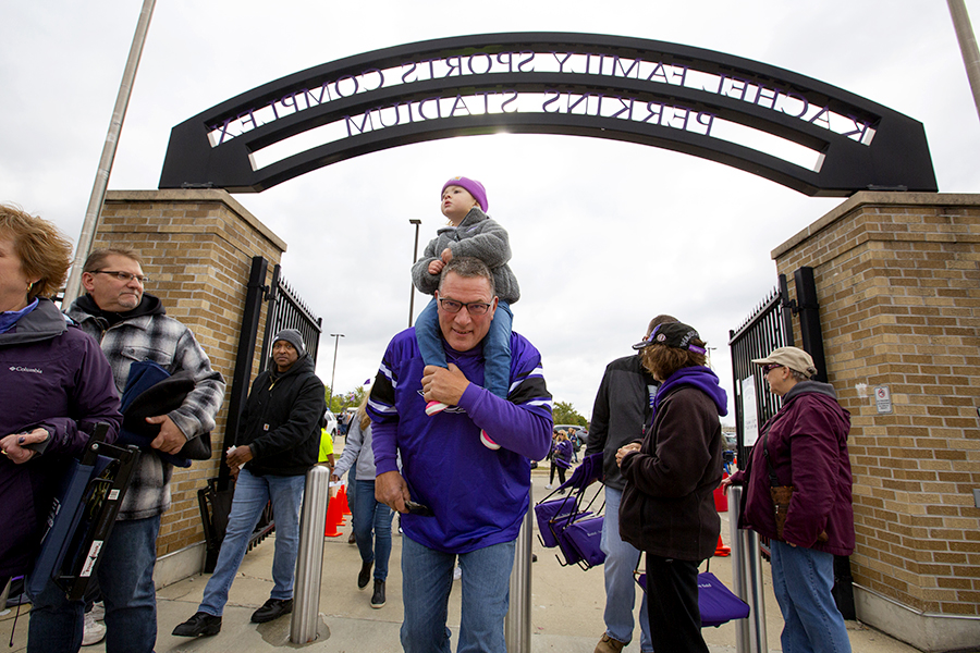 A young grandparent carries a child on their shoulders as people leave Perkins Stadium.