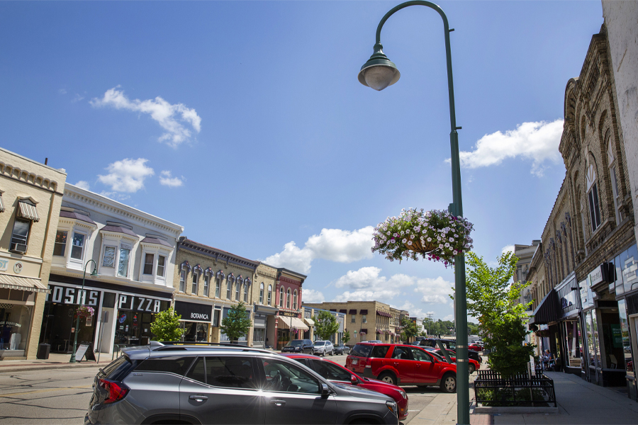 Buildings line the street in Downtown Whitewater with colorful flower pots hanging on the light posts.