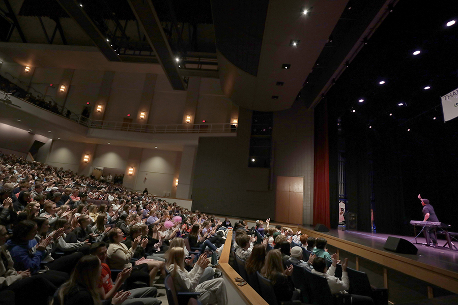 Students fill the seats and watch someone perform on stage inside the Young.