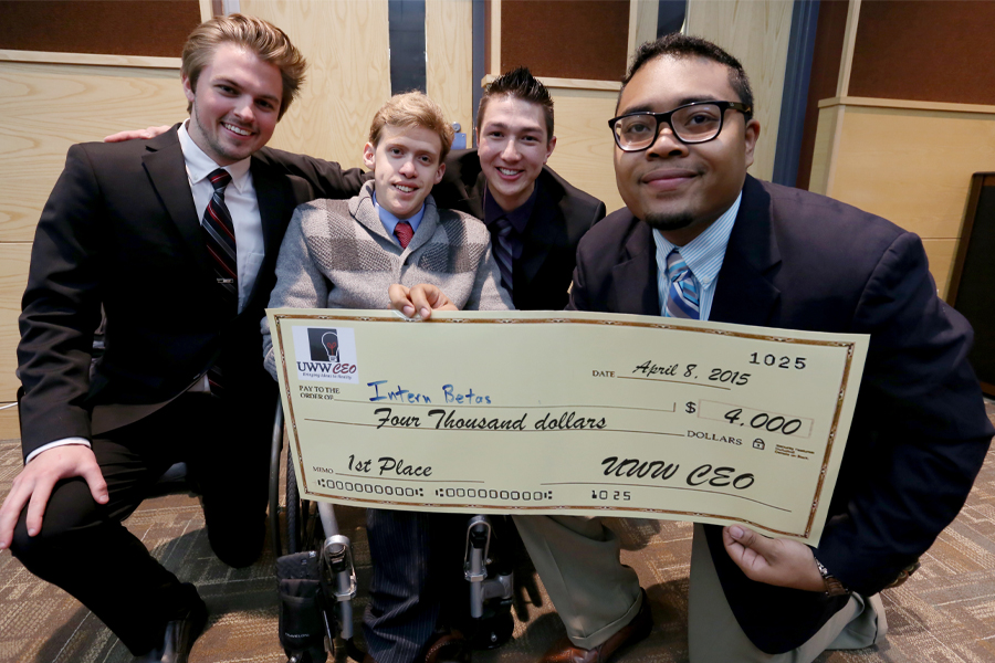 Four students hold a large check.