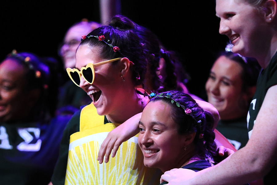 A group of UW-Whitewater students laugh together with one wearing a yellow shirt and yellow novelty sunglasses.