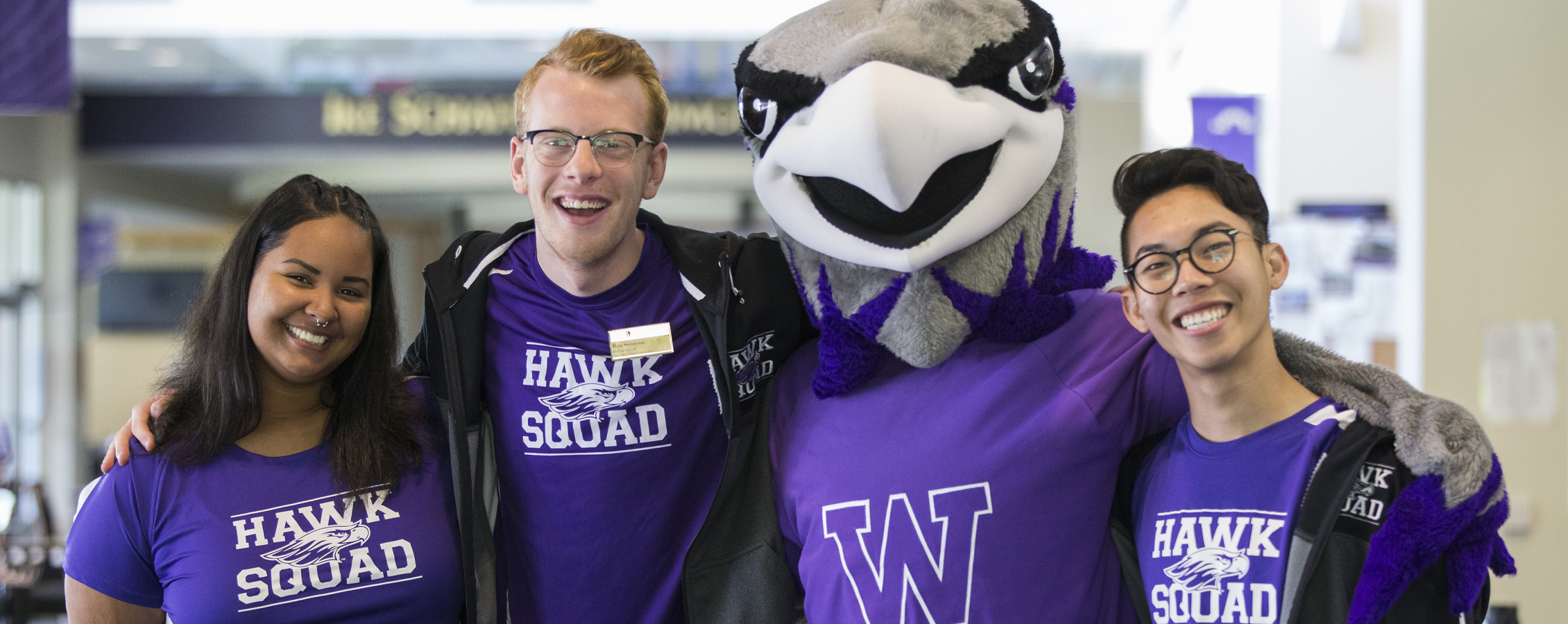 Three students pose for a photo with Willie the Warhawk.