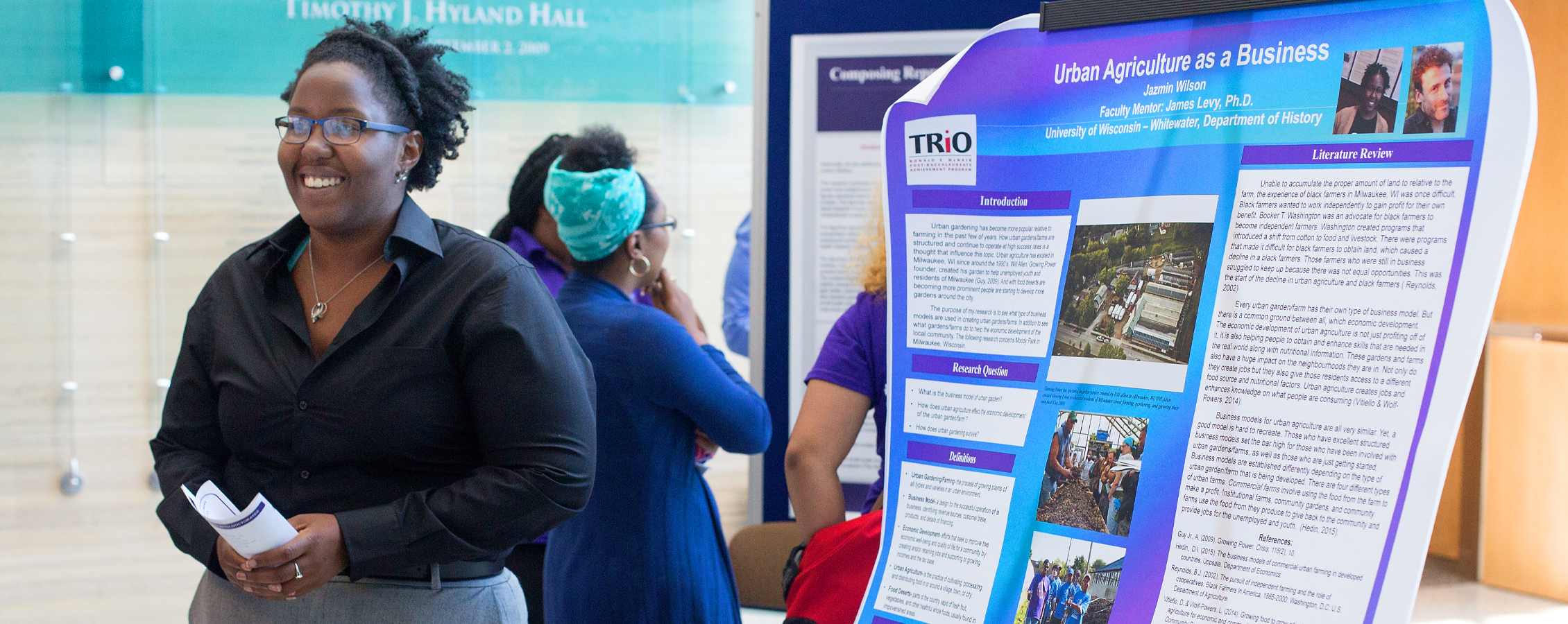 Student stands next to her undergraduate research poster.