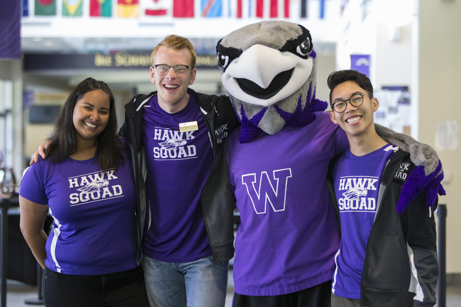 Three students stand with Willie Warhawk.